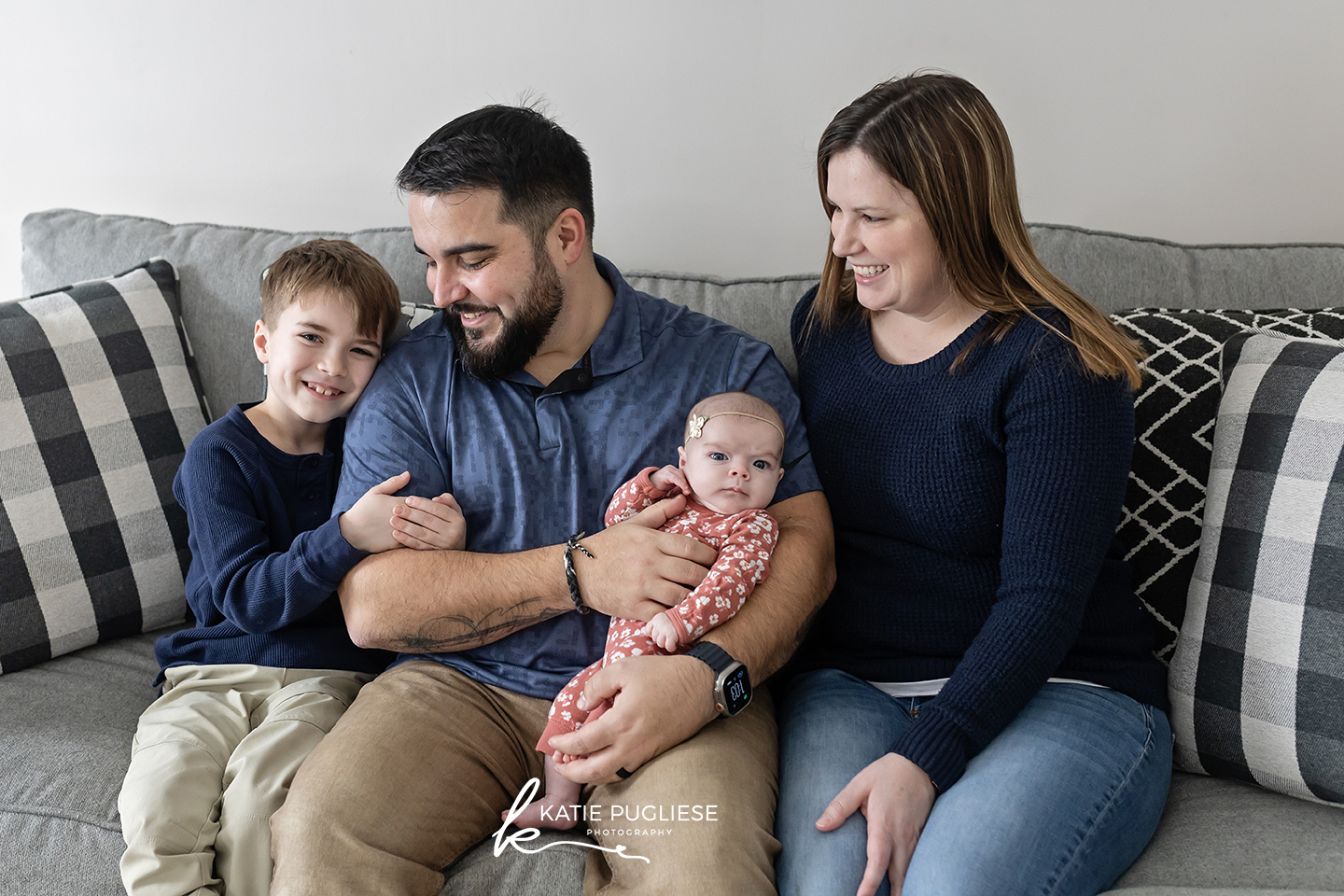 Family of four sitting on couch with newborn baby